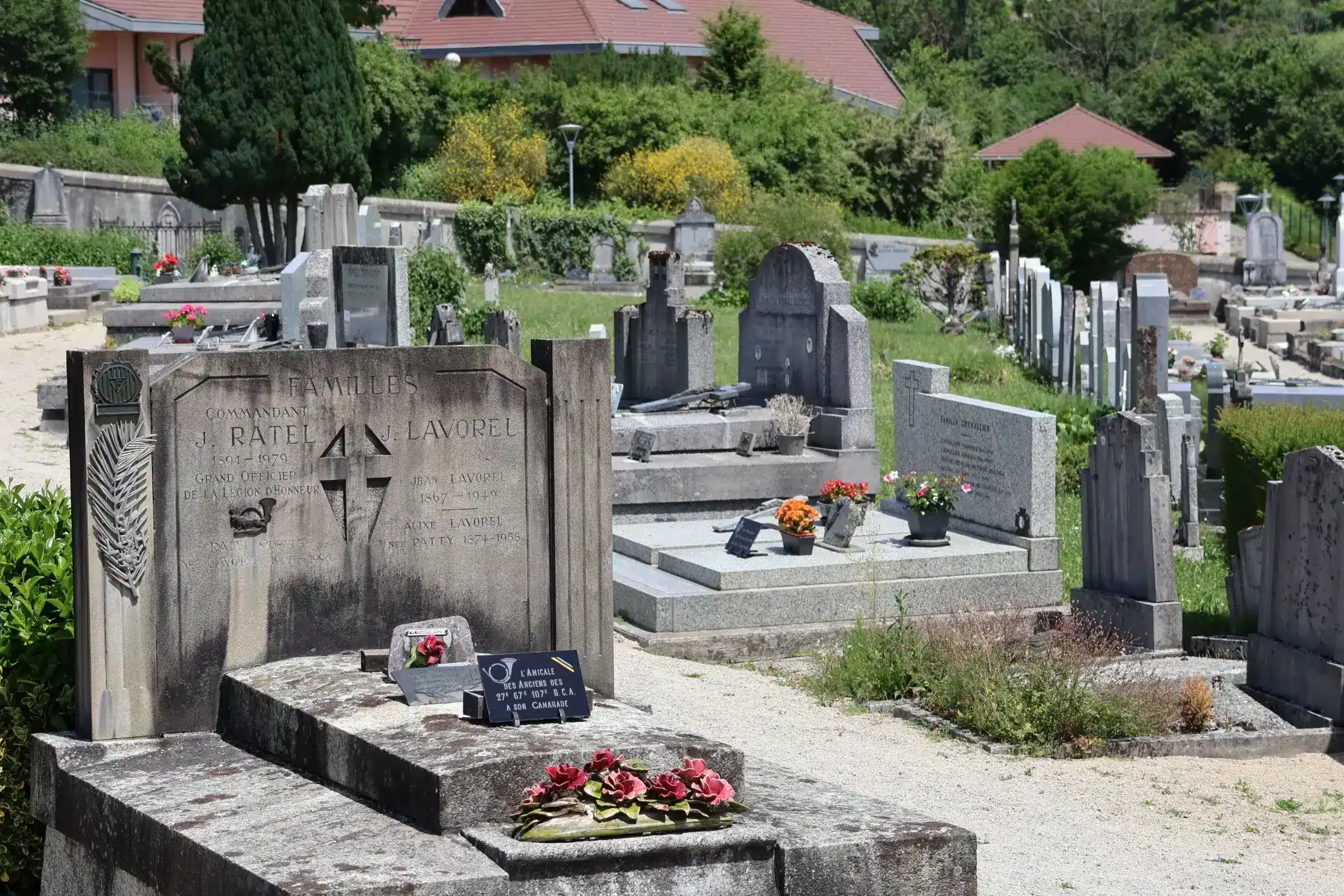 Tombeau et carré funéraire dans un cimetière professionnel, avec pierres tombales gravées et bouquets fleuris sur les débris.