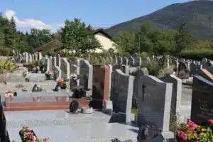 Allée de tombes en cimetière avec des monuments en pierre et des fleurs fraîches déposées sur plusieurs pierres tombales. fleurs à mettre au cimetière en ce moment, ambiance paisible.