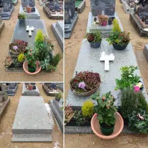 Tombe entourée de pots de fleurs et feuillages colorés sur un cimetière, éléments décoratifs et croix blancs visibles sur le